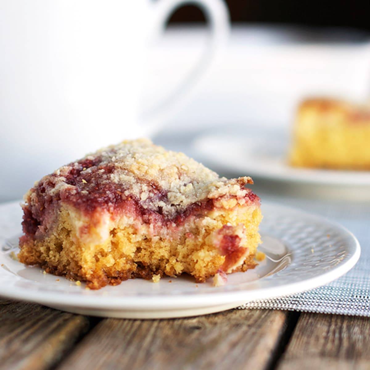Raspberry cream cheese coffee cake with a bite taken out on a plate.
