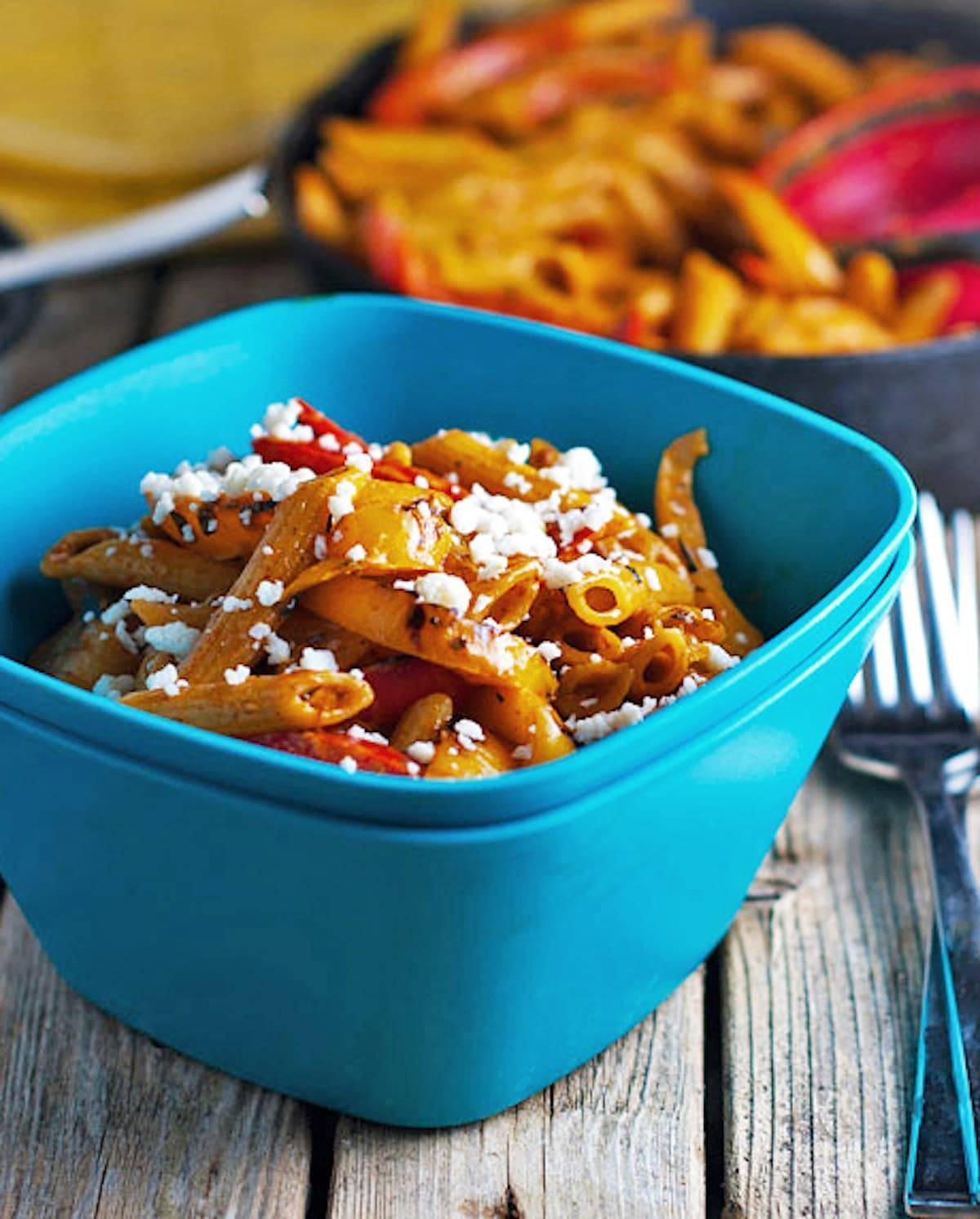 Skinny shrimp fajita pasta topped with cheese in a blue bowl.