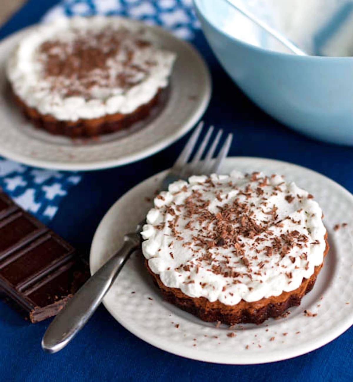 Two French silk brownie pies on white plates with a fork.
