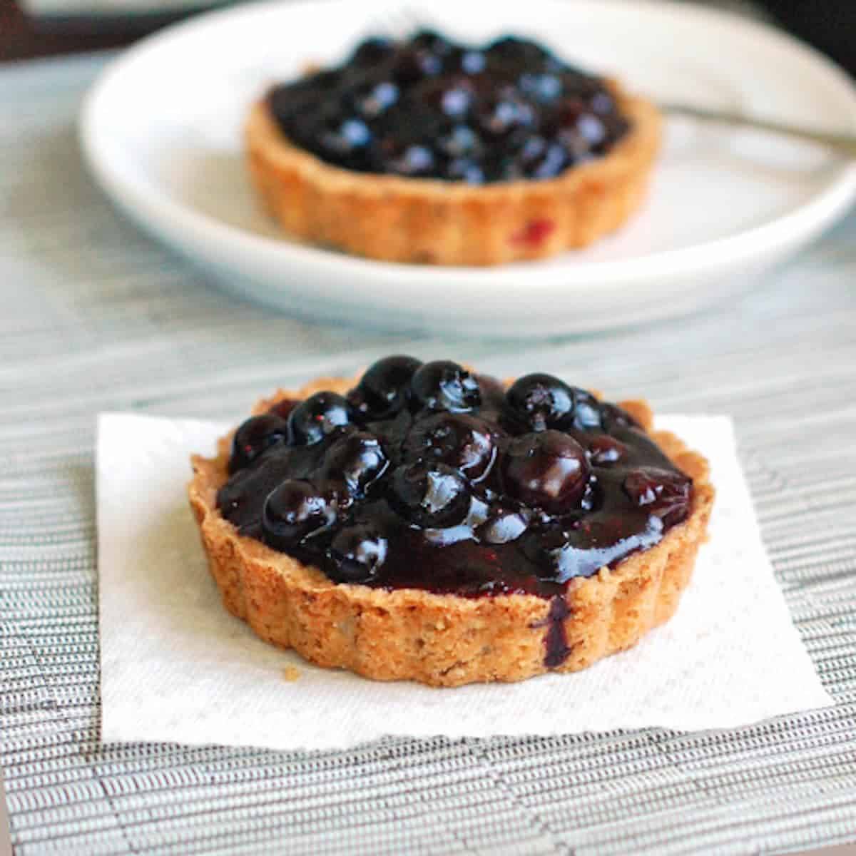 Two blueberry tarts with homemade crust and packed full of fresh blueberry filling.