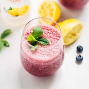 Frosted Blueberry Lemonade in a glass with lemons and blueberries.