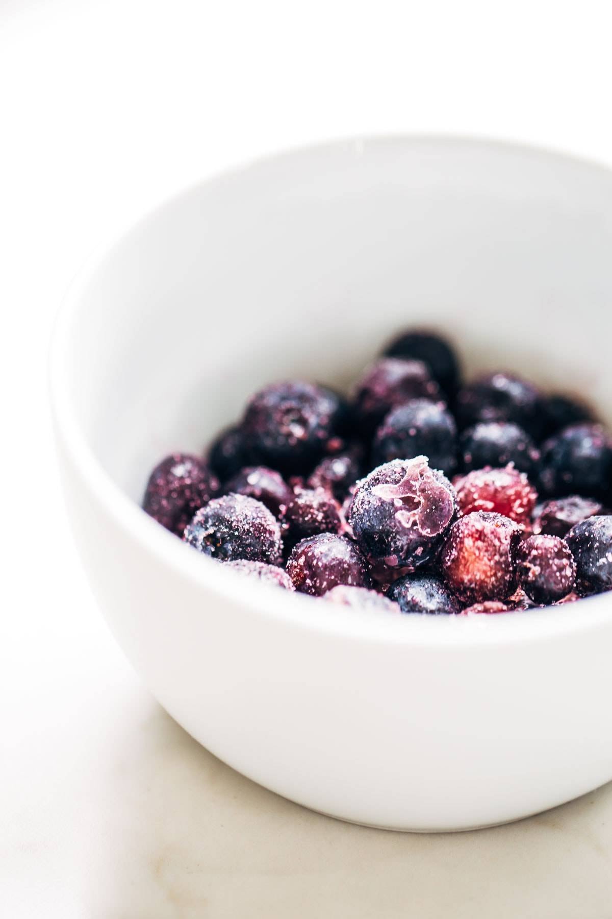 Frozen blueberries in a white bowl.