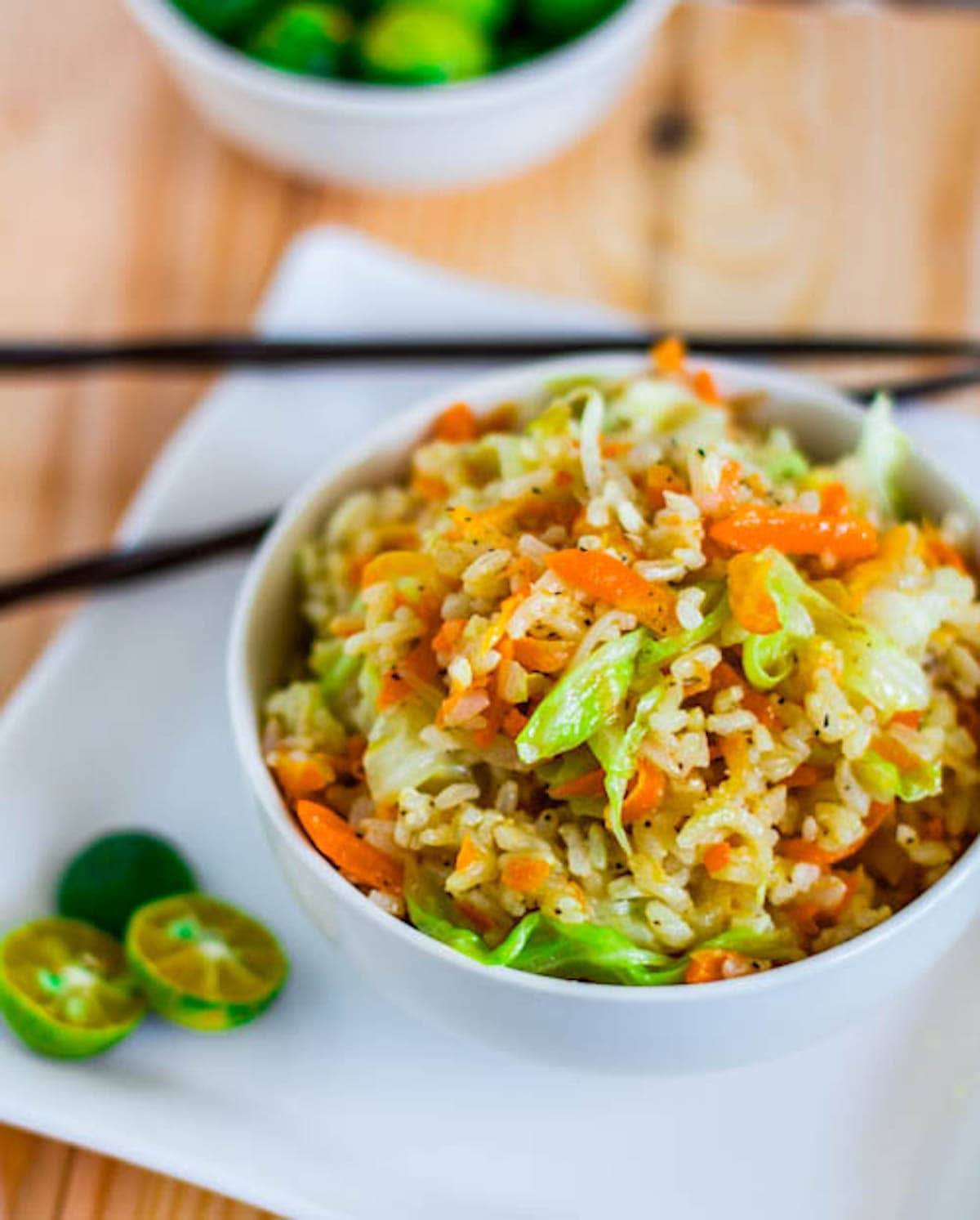 Skinny Garlic Fried Rice in a bowl with limes and chopsticks.