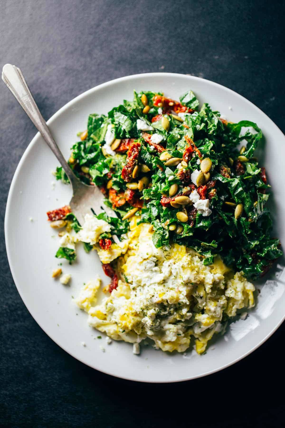 Goat Cheese Scrambled Eggs with Pesto Veggies on a white plate with a fork.