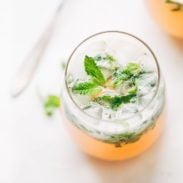 Grapefruit Mojitos in a glass with mint leaves.