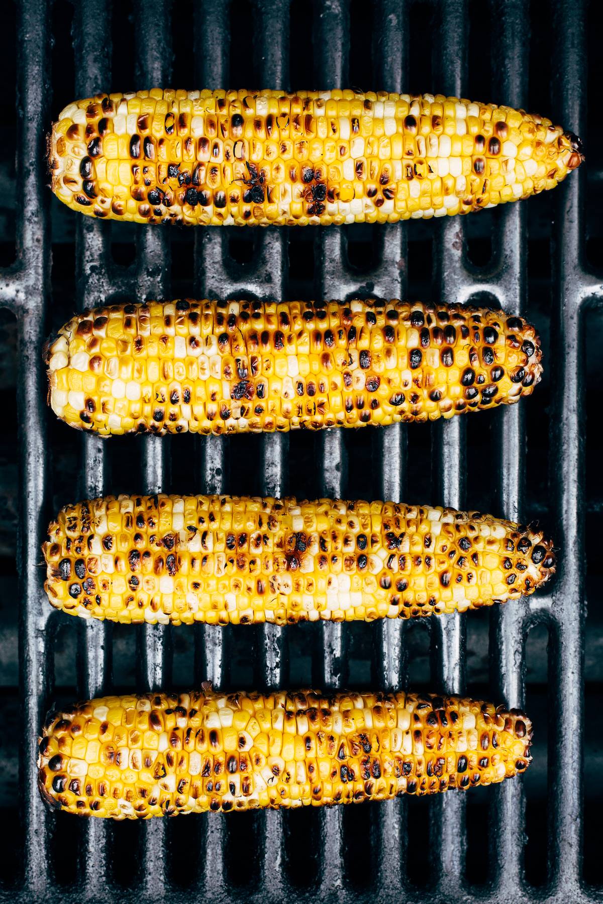 Four ears of corn directly on grill grates.