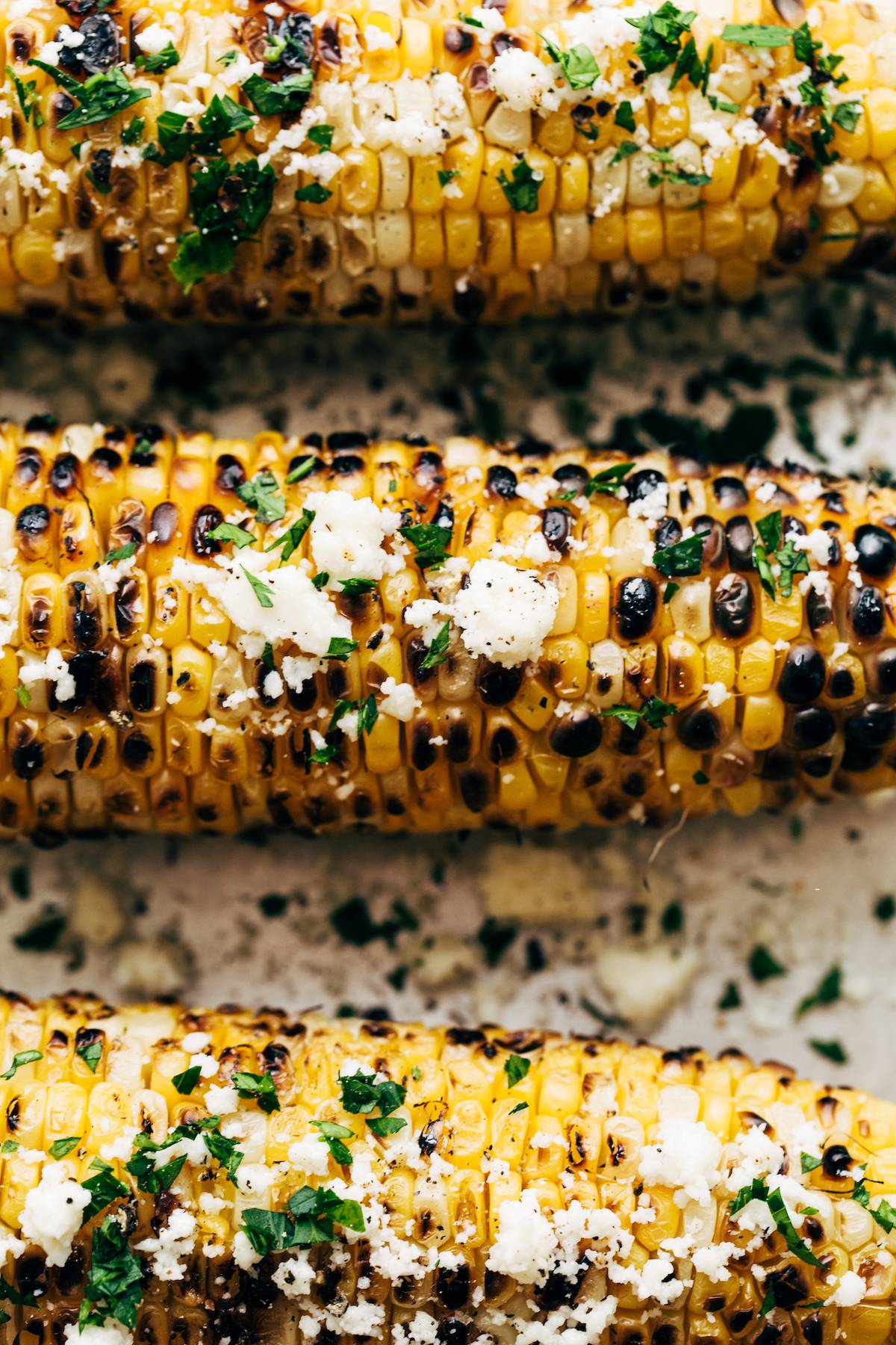 Close-up image of grilled corn with cheese on top.