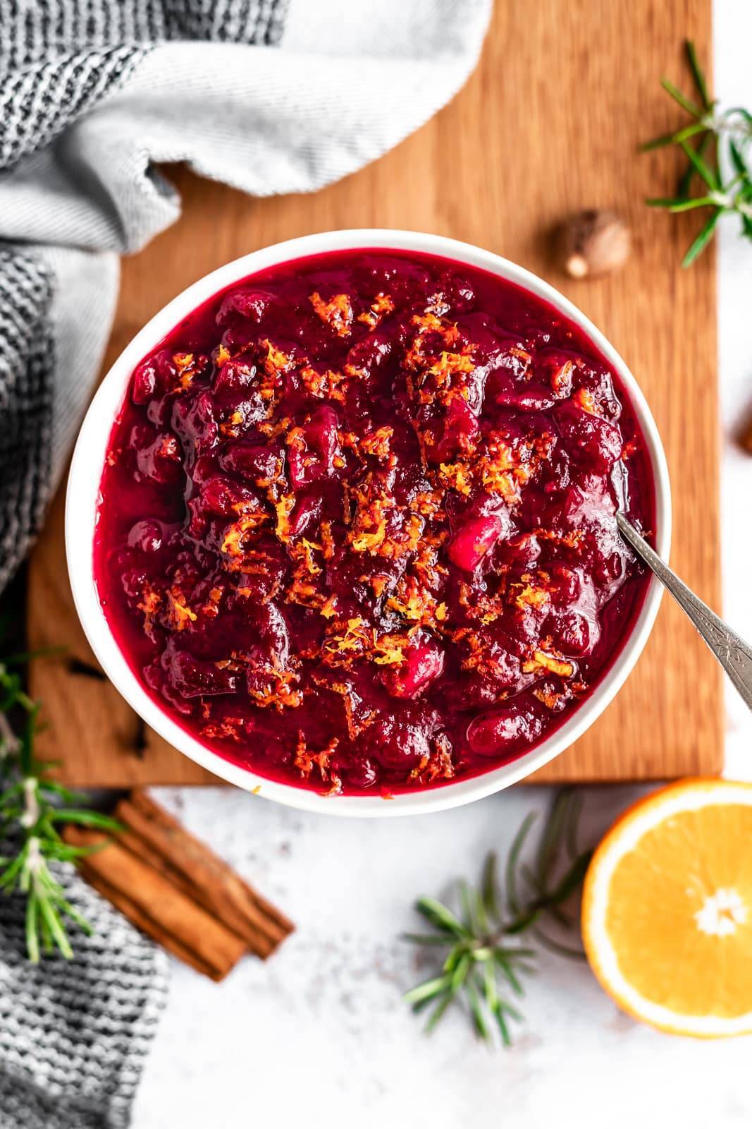 Orange cranberry sauce in a bowl with a spoon.