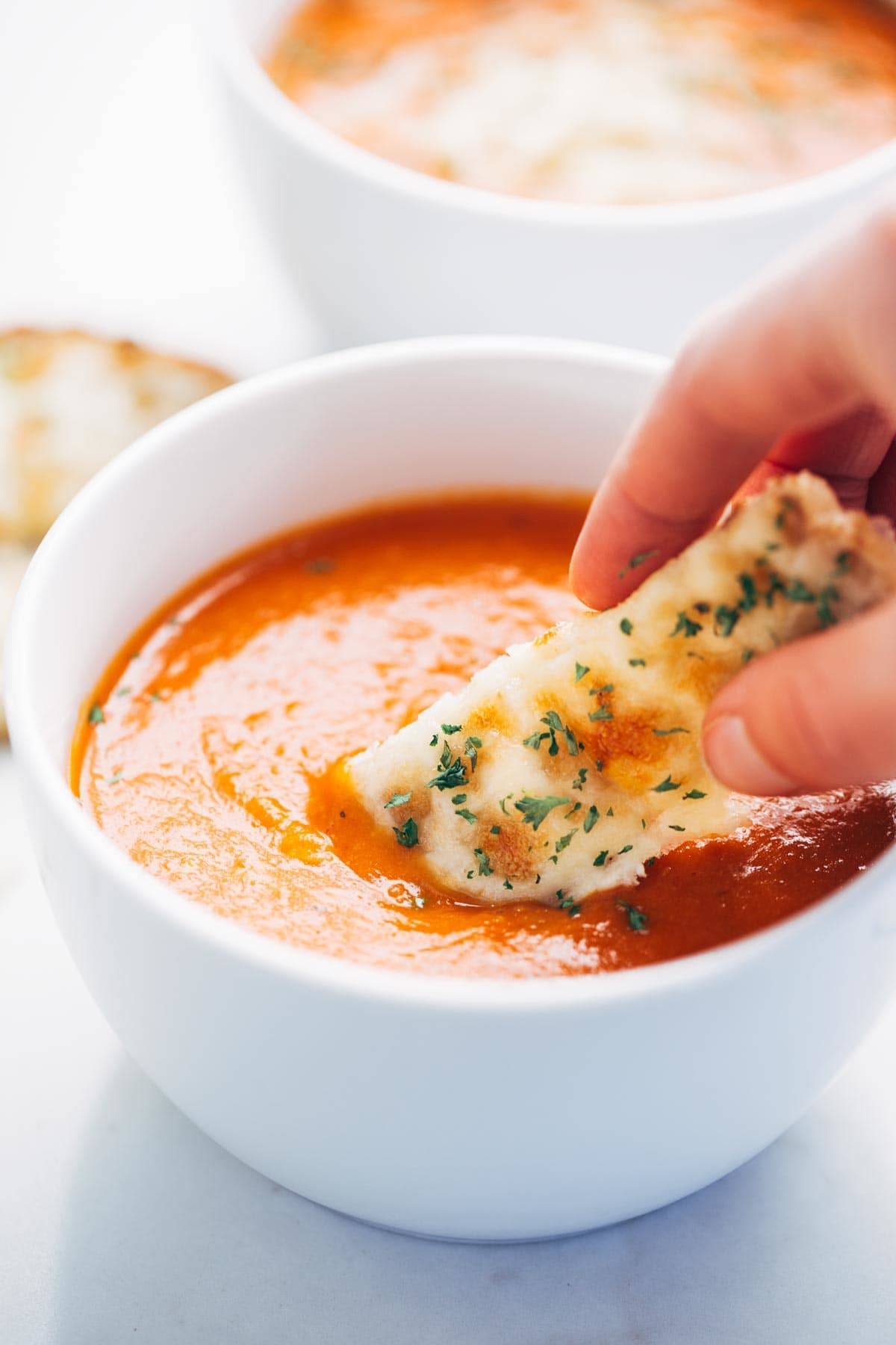Homemade tomato soup in a bowl with bread dipped in.