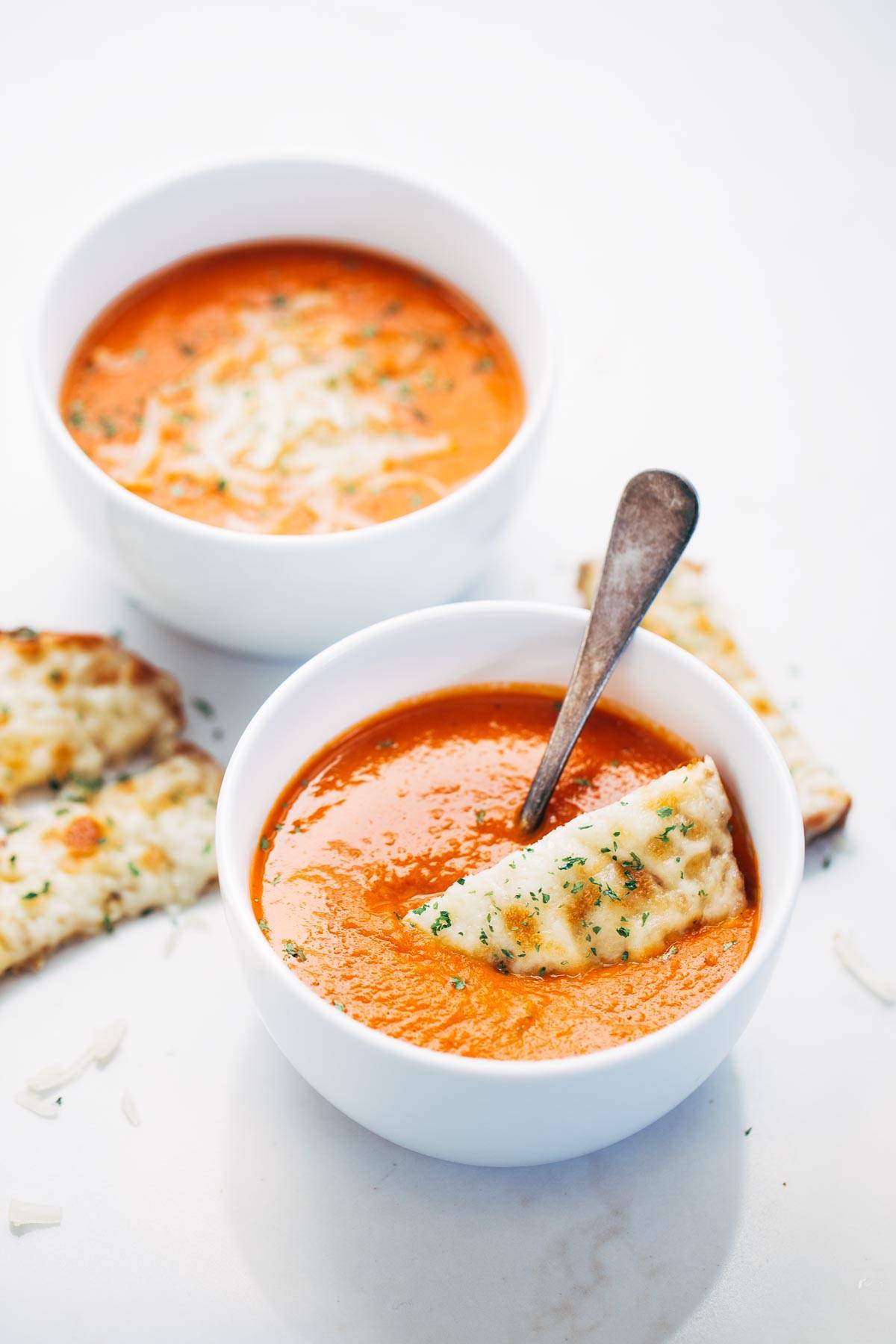Tomato soup in bowls with cheese and bread.