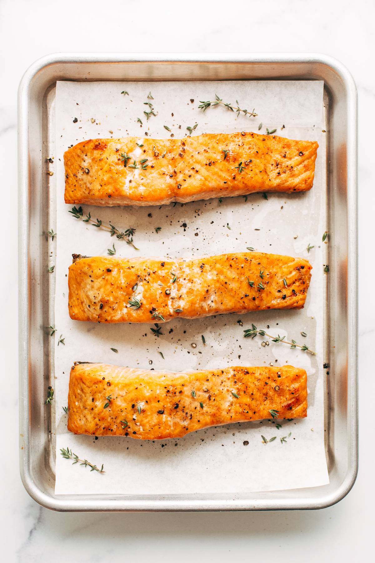 Three fillets of salmon baked on a sheet pan.