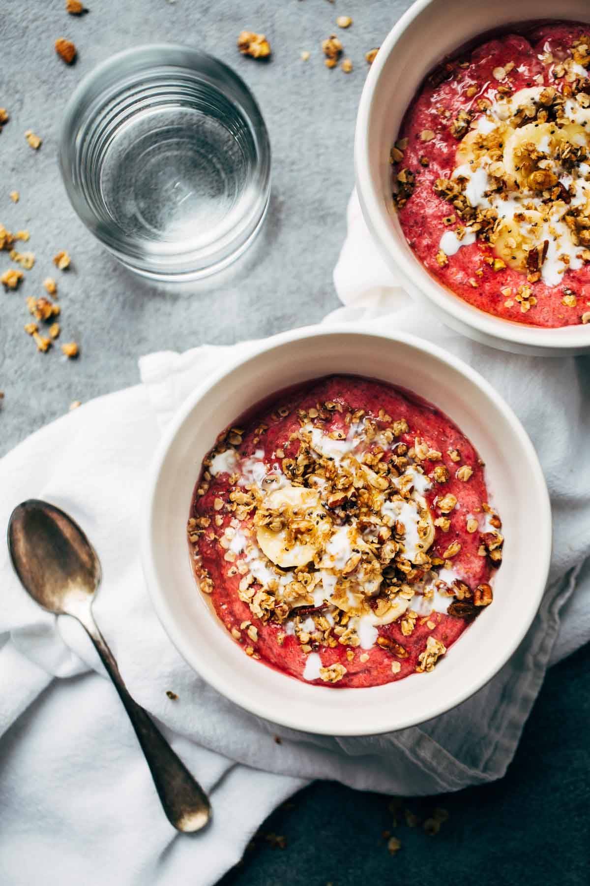 Raspberry Breakfast Bowls on a napkin with a spoon and a glass of water.