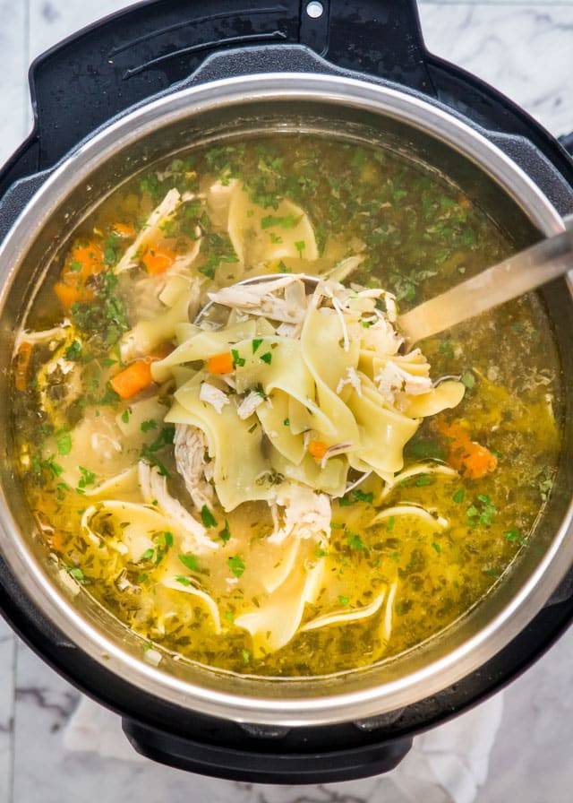 Chicken noodle soup in a bowl with a spoon.