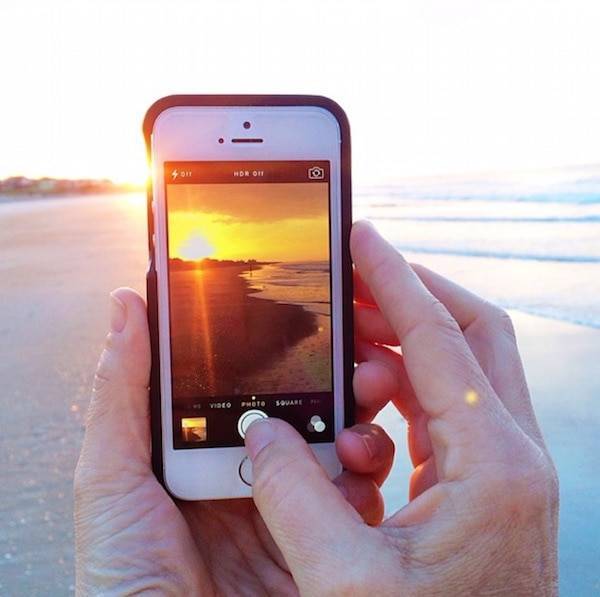 Iphone taking a photo of the sunrise.