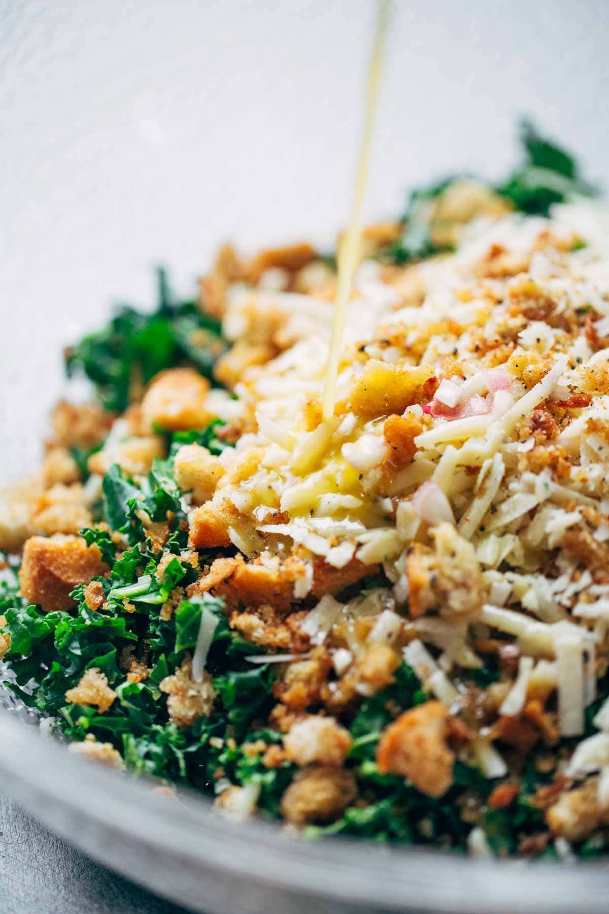 Kale salad in a mixing bowl with cheese and breadcrumb toppings.