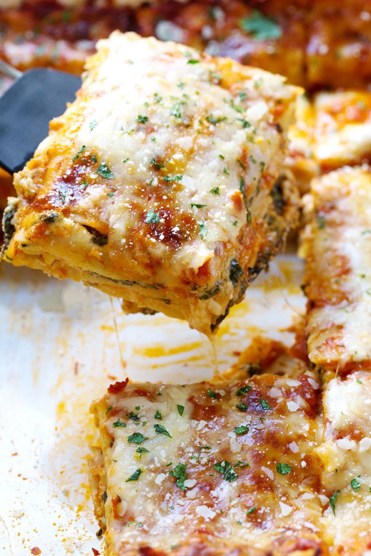 Lasagna in a pan with a piece on a spatula.