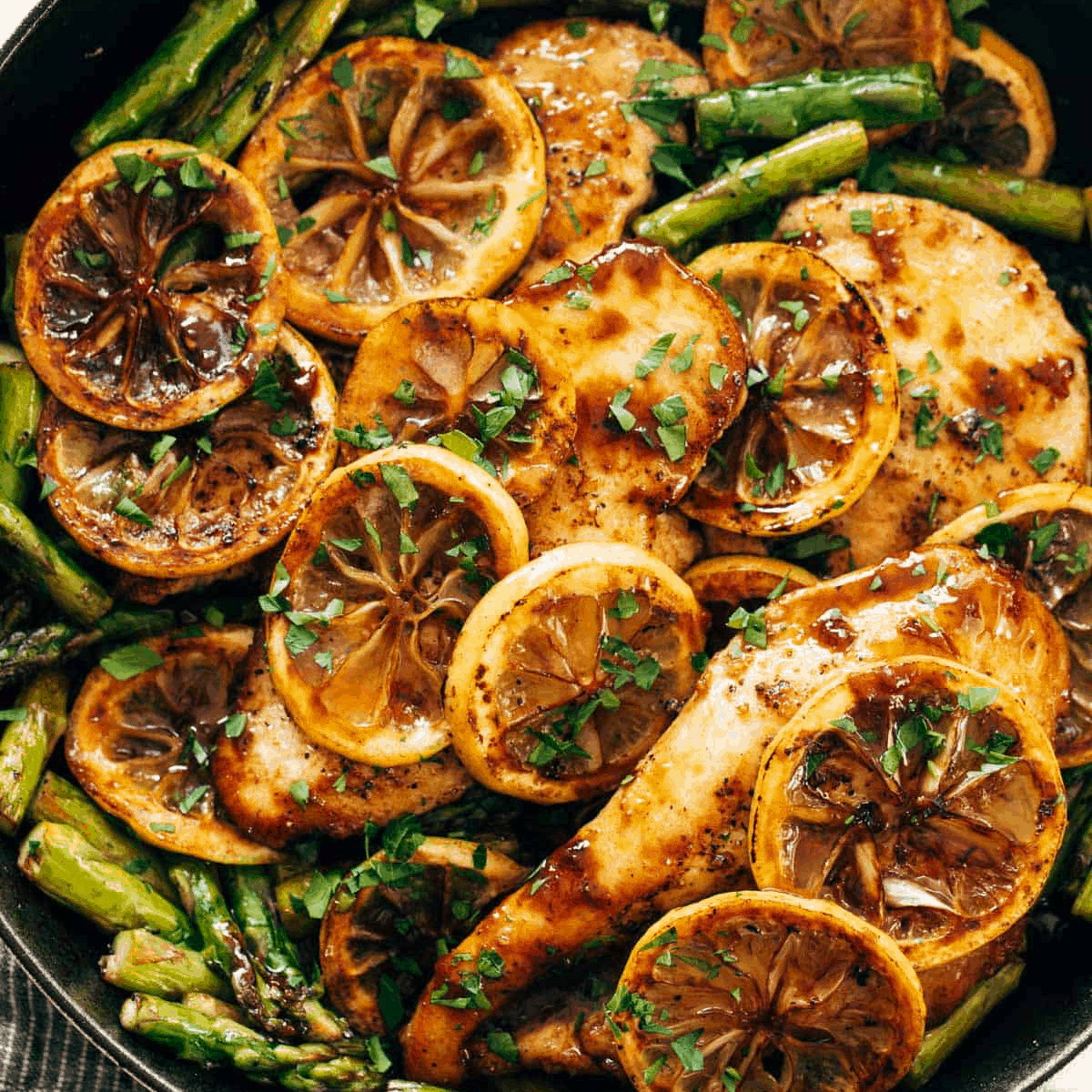 Asparagus and chicken with slices of lemon on it.