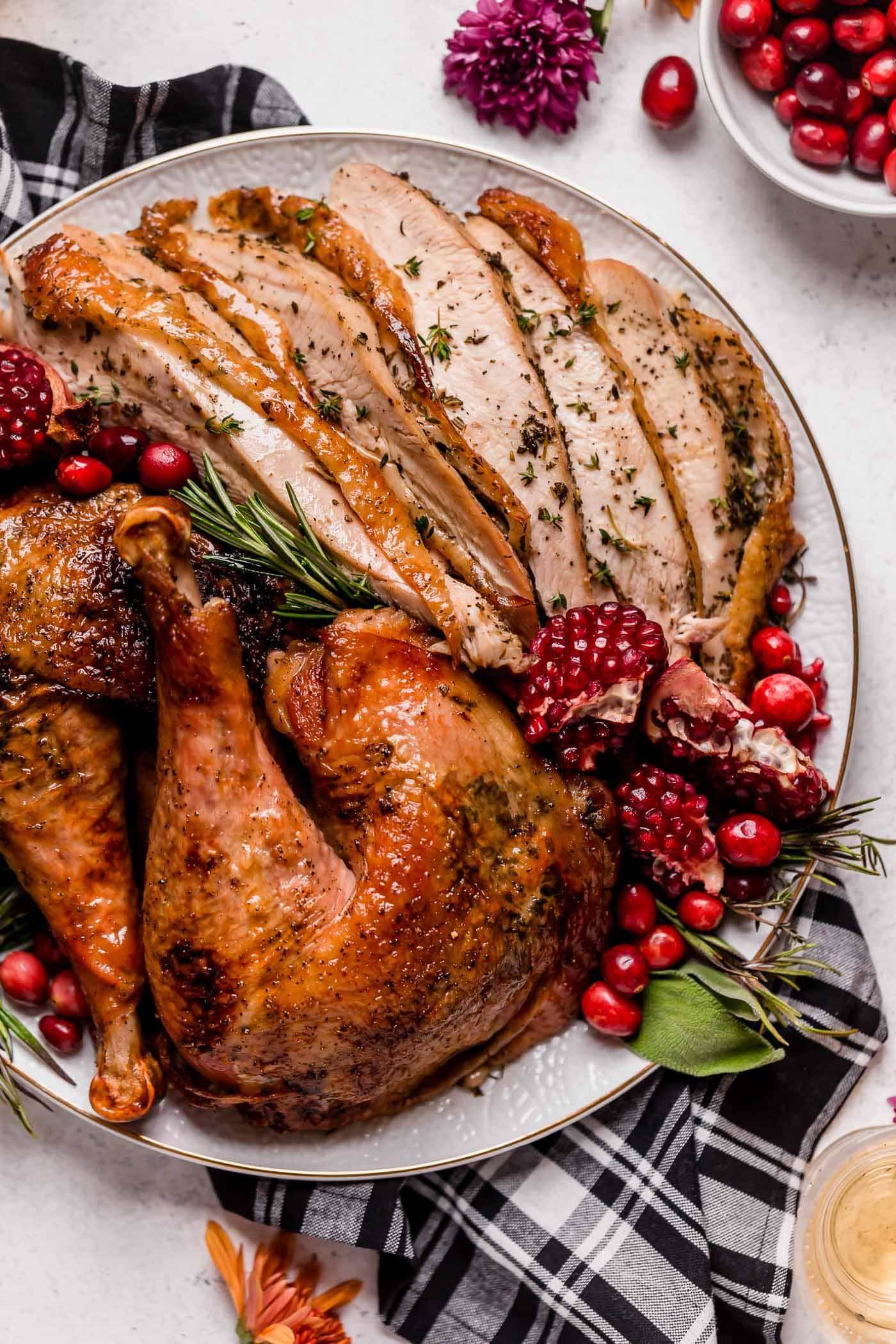 Maple Glazed Spatchcock Turkey on a platter with pomegranate arils and cranberries