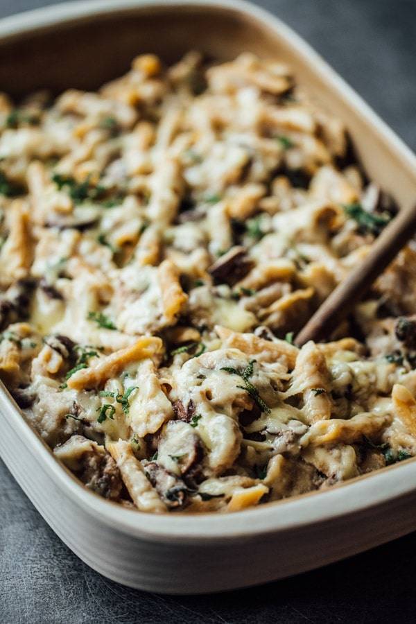 Healthy Mushroom Alfredo Pasta Bake in a dish with a wooden spoon.