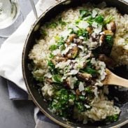 Mushroom risotto in pan with wooden spoon.