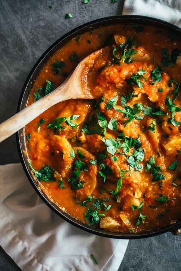 Spanish Chicken and Potatoes in a black skillet with a wooden spoon.