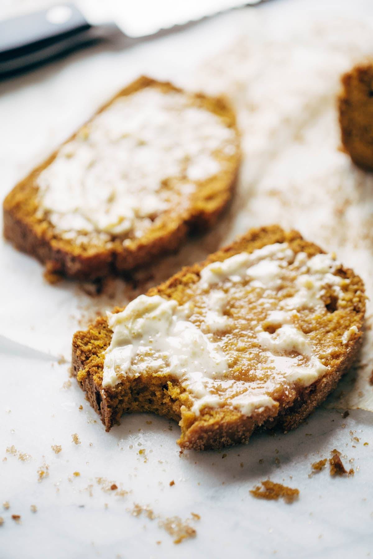 Two pieces of pumpkin bread with butter spread over it.