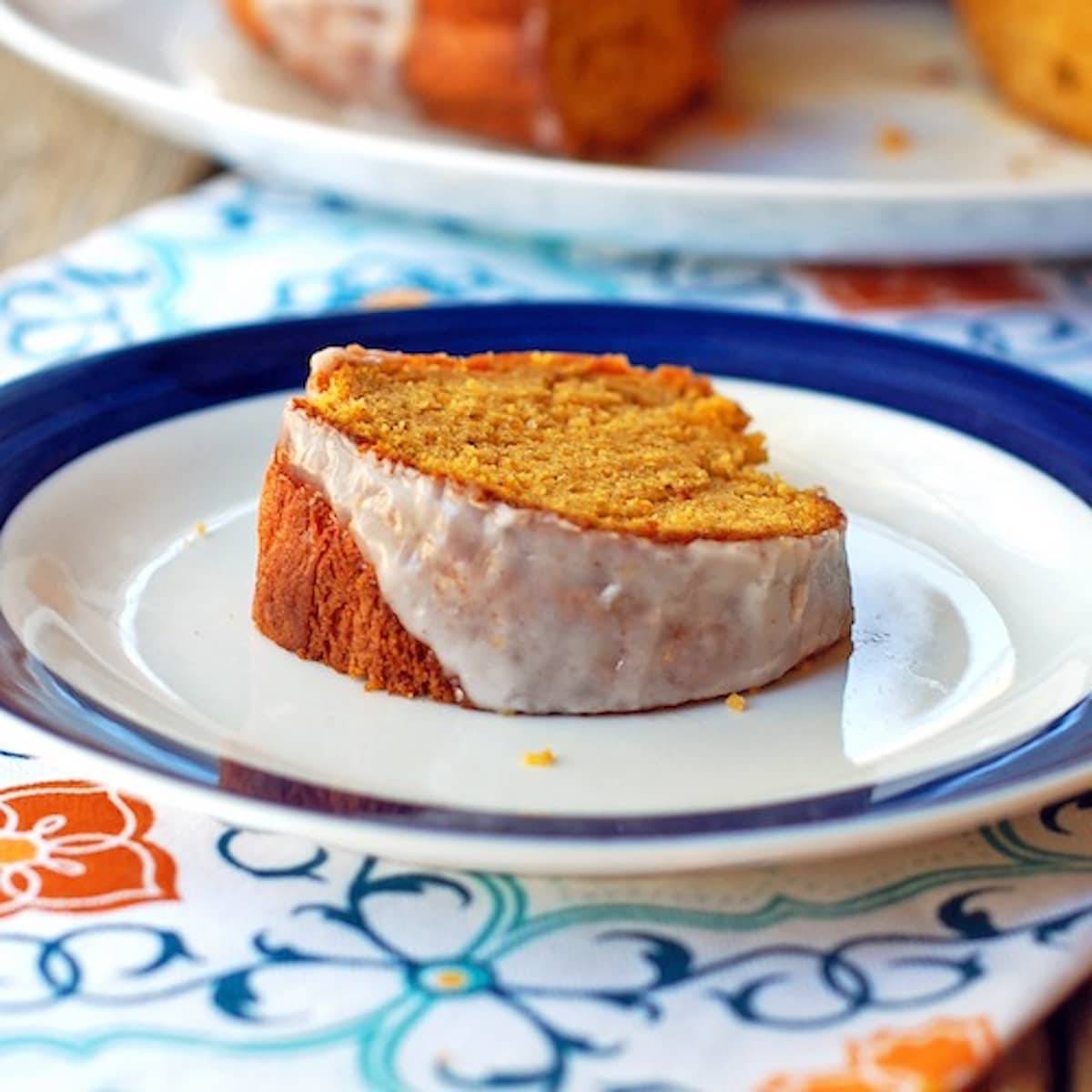 Pumpkin bundt cake with cinnamon glaze on a white plate on a colorful napkin.