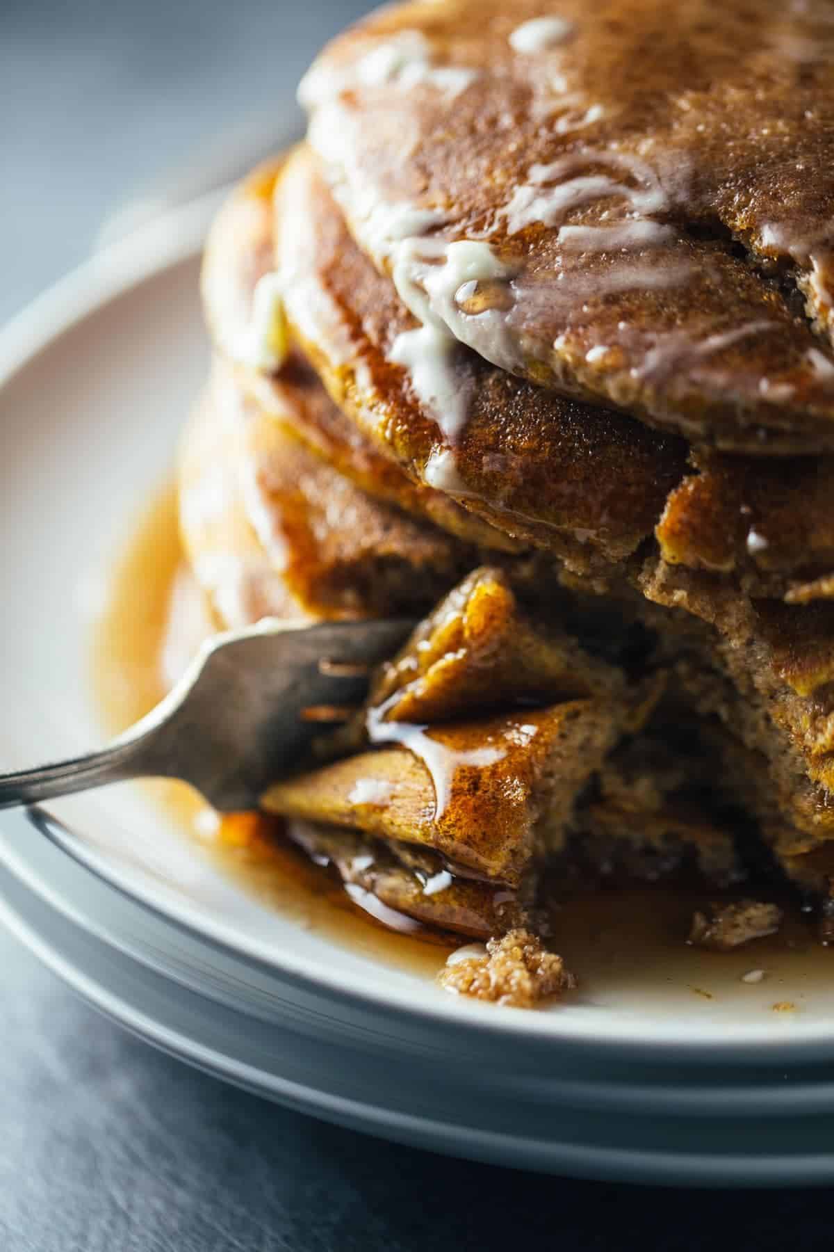 Cinnamon Pumpkin Pancakes stacked on a plate and on a fork.