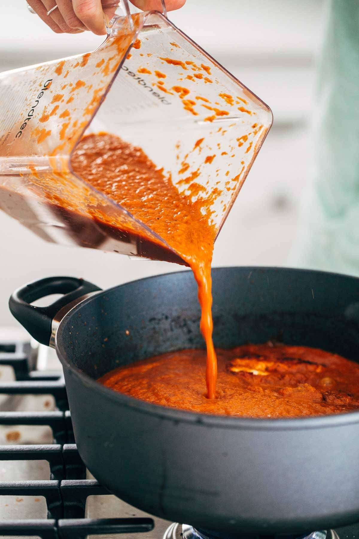 Sauce in a blender pouring into a skillet.