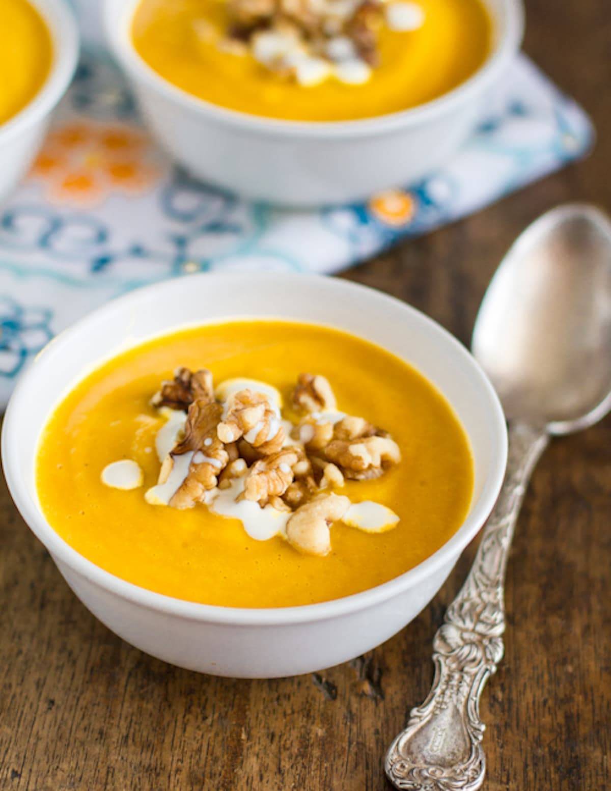 Two bowls of creamy squash soup with a spoon.