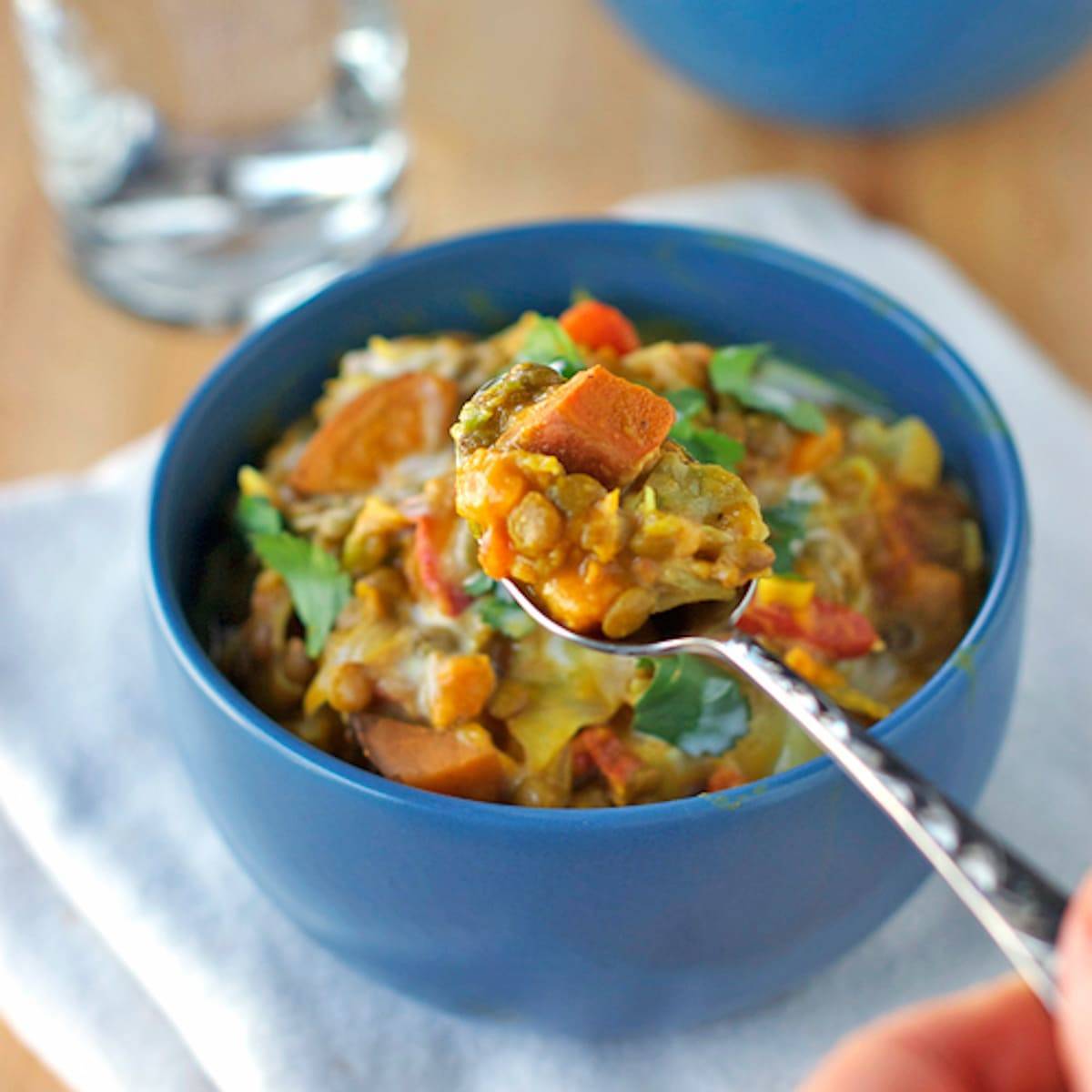 Creamy Thai sweet potatoes and lentils in a blue bowl and on a spoon.