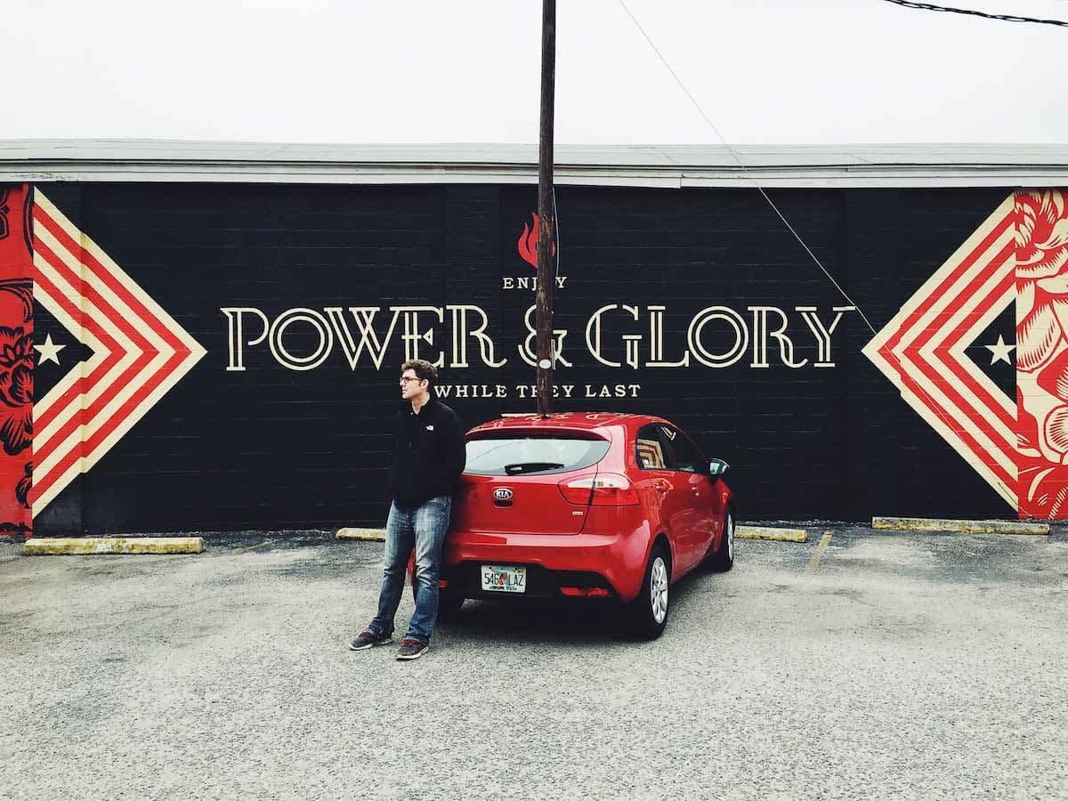 Power and Glory sign and a man standing next to a car.