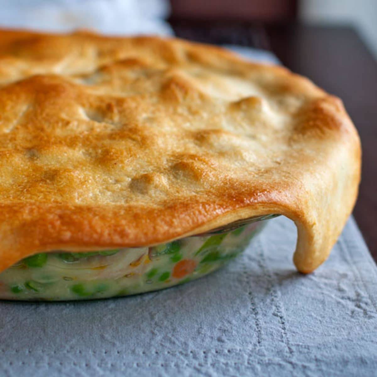 Garlic chicken and vegetable pot pie in a pan on a blue napkin.