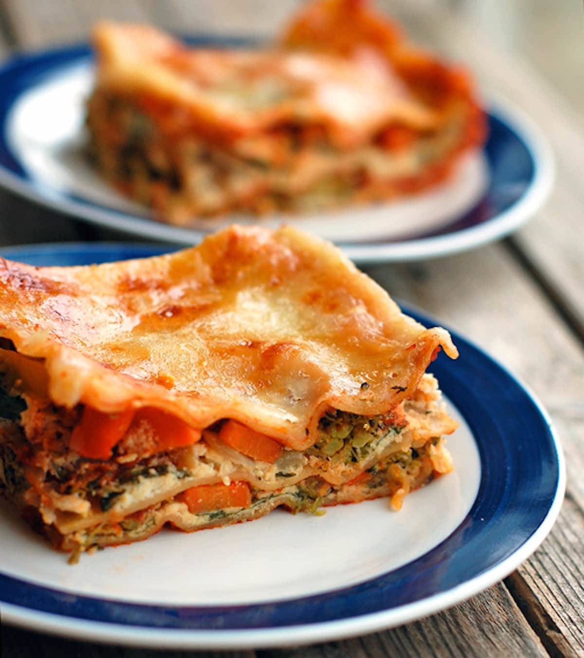 Veggie lasagna full of chopped broccoli, carrots, cauliflower, spinach, ricotta cheese, and tomato sauce on a plate.