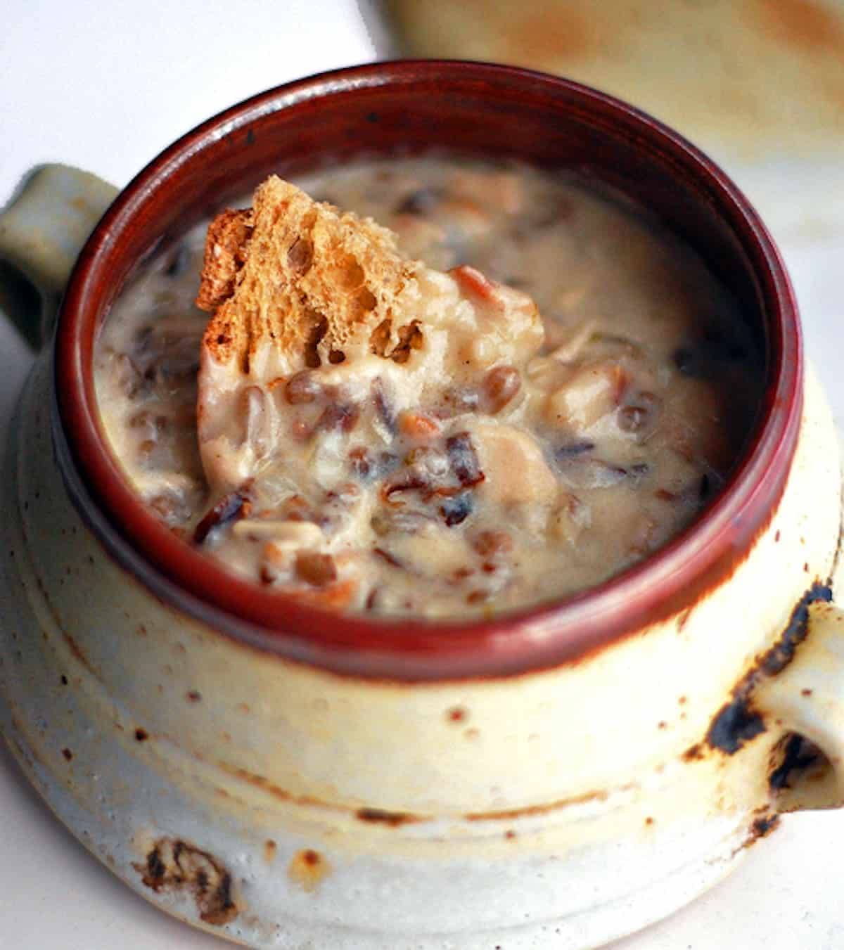 Chicken bacon wild rice soup with bread in a bowl.