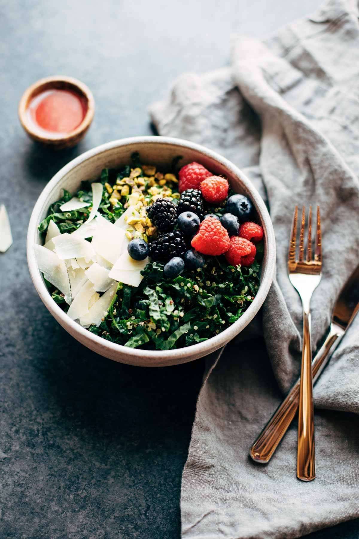Bowl with greens and berries with fork and knife.