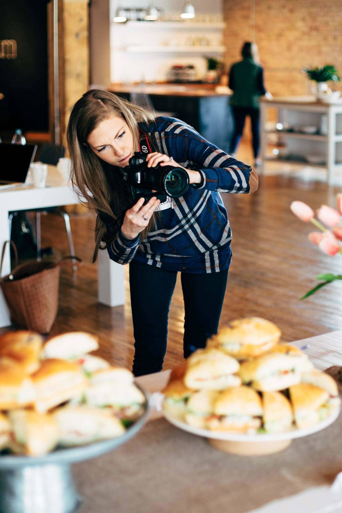 Woman photographing sandwiches.