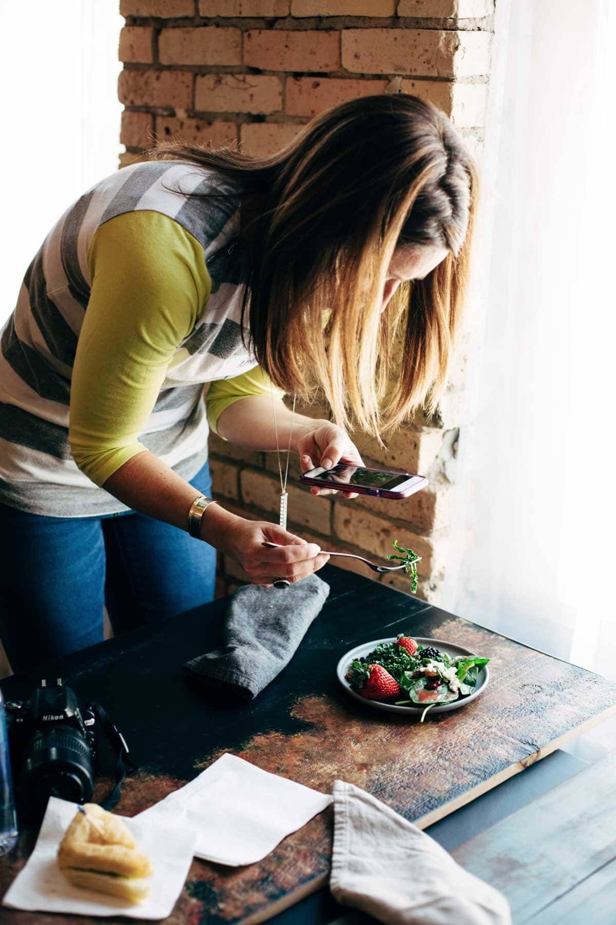 Woman taking a photo of salad with her phone.